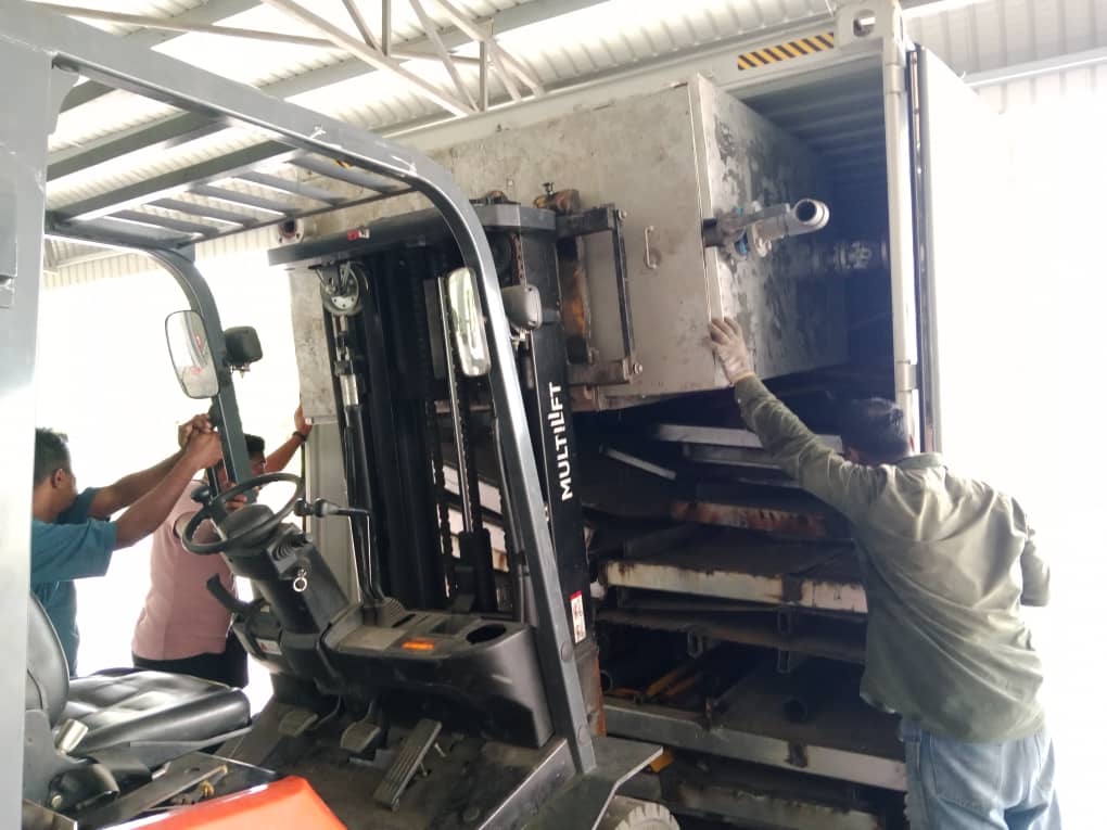 Team guiding large module into container using forklift